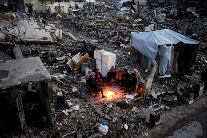 Palestinians gather around a fire, amid the rubble of destroyed buildings in the Jabalya refugee camp in the northern Gaza Strip on Feb. 13 Mahmoud Issa Reuters 250213 - Gaza - Trump - piano
